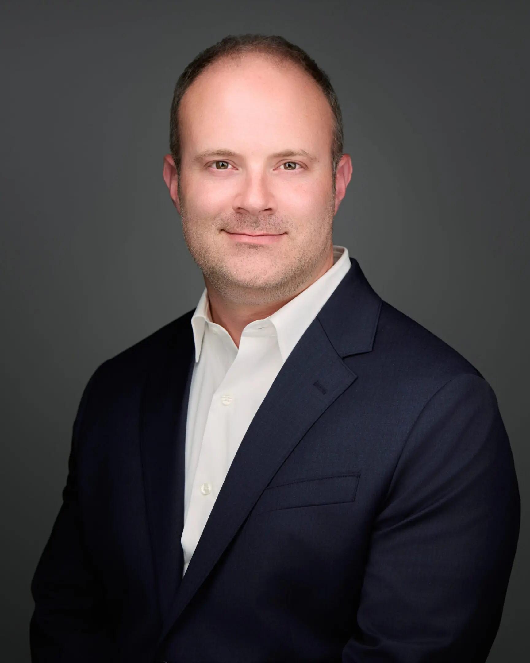 Professional headshot of a man in a suit with a neutral background.