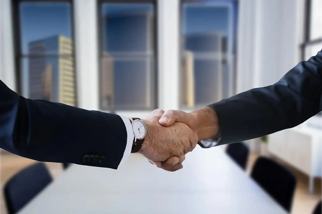 Two business professionals shaking hands in an office.